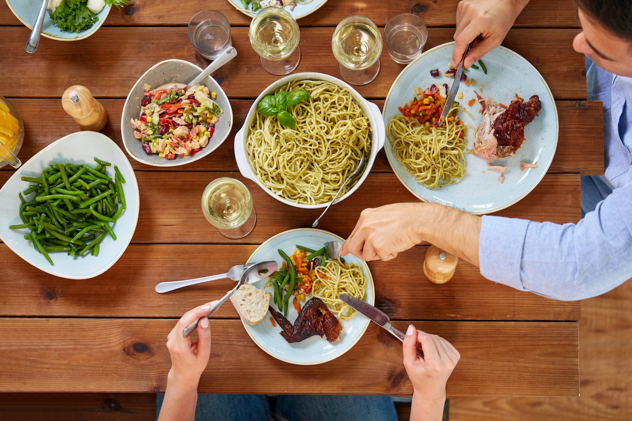 couple at table with food eating pasta and chicken